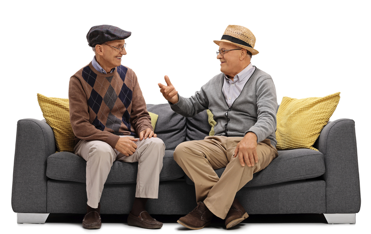 zwei ältere Männer sitzen auf einem Sofa und reden