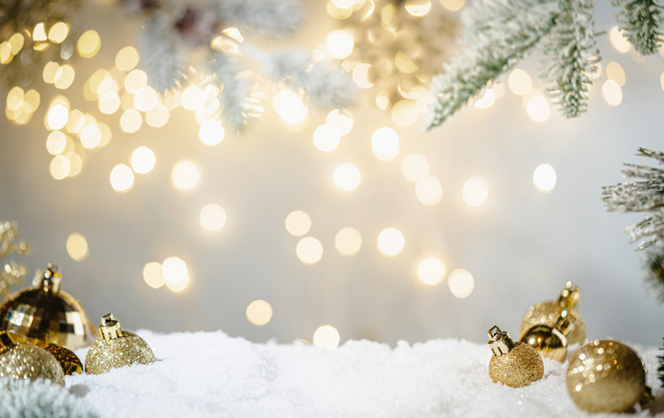 Weihnachtsfeiertagshintergrund mit Schnee, Tannenbaum und Dekorationen mit Weihnachtslicht dahinter
