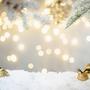 Weihnachtsfeiertagshintergrund mit Schnee, Tannenbaum und Dekorationen mit Weihnachtslicht dahinter