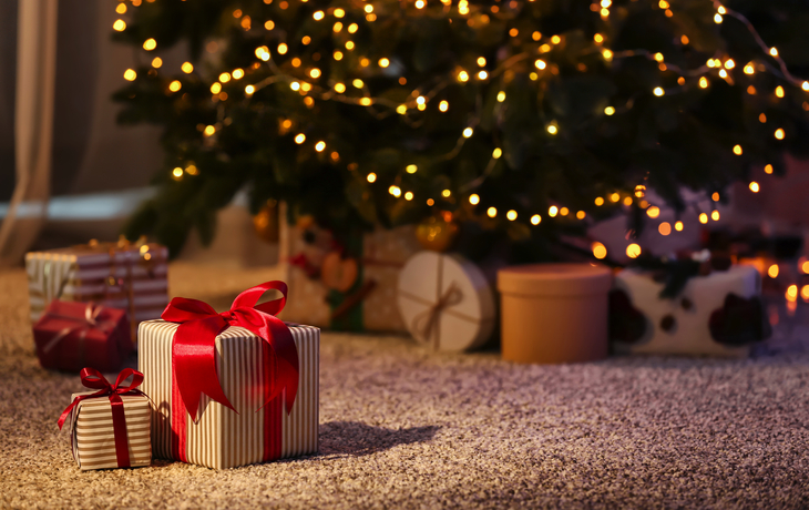 Weihnachtsgeschenkboxen auf dem Boden neben der Tanne im Zimmer