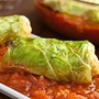 Vegetarische Kohlroulade gefüllt mit Reis, Paprika, Zwiebel und Karotte, serviert auf Tomatensauce, fotografiert mit natürlichem Licht (Selektiver Fokus, Fokus auf die Vorderseite der Roulade)