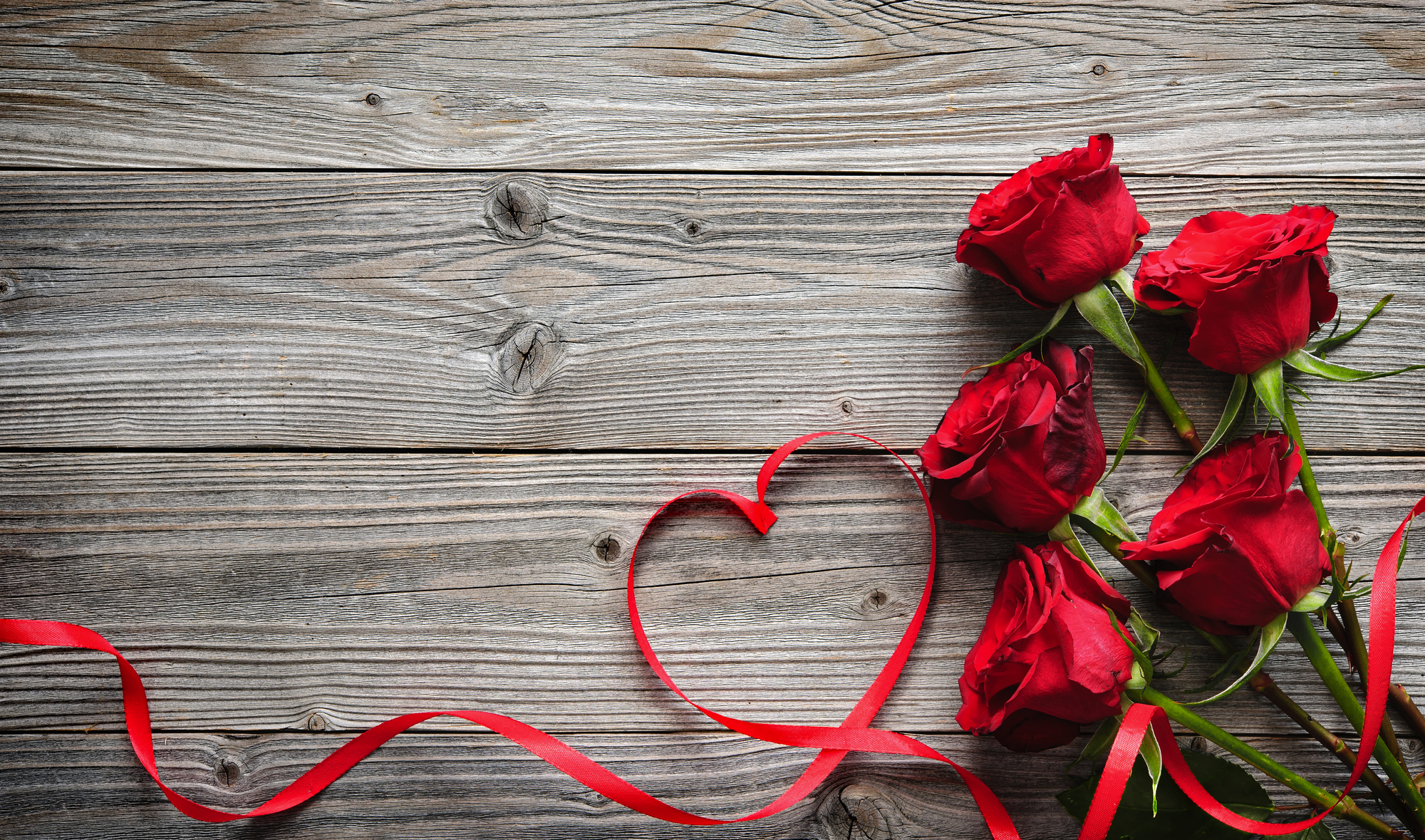 rote Rosen und Band auf hölzernem Hintergrund
