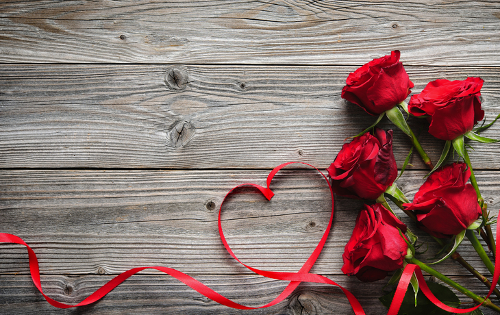 rote Rosen und Band auf hölzernem Hintergrund