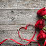 rote Rosen und Band auf hölzernem Hintergrund