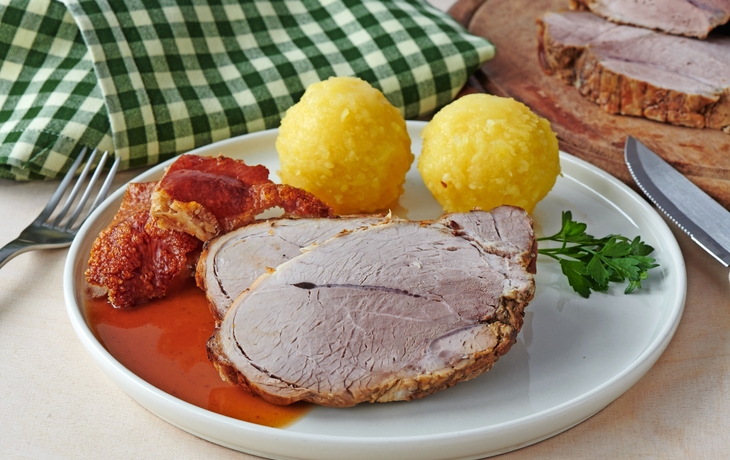 Deutscher Schweinebraten mit Kruste und Knödel auf weißem Hintergrund 