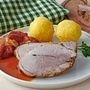 Deutscher Schweinebraten mit Kruste und Knödel auf weißem Hintergrund 