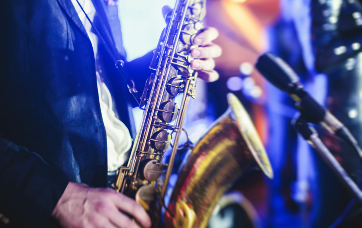 Konzertansicht eines Saxophonisten mit Sänger und musikalischer Jazzband im Hintergrund