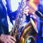 Konzertansicht eines Saxophonisten mit Sänger und musikalischer Jazzband im Hintergrund