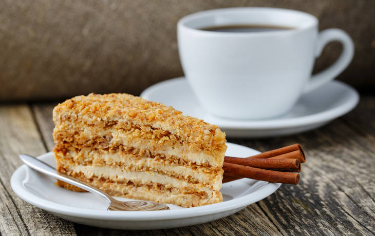 Geschmackvoller Honigkuchen mit Tasse Kaffee auf hölzernem Hintergrund.