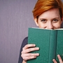 lachende frau versteckt sich hinter einem buch
